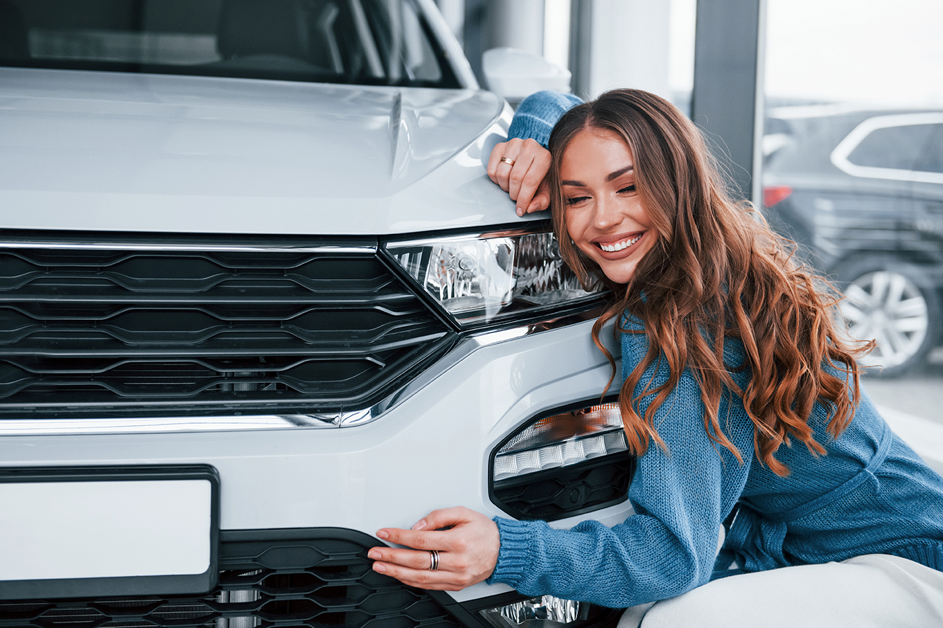 woman hugging a car at the car dealership